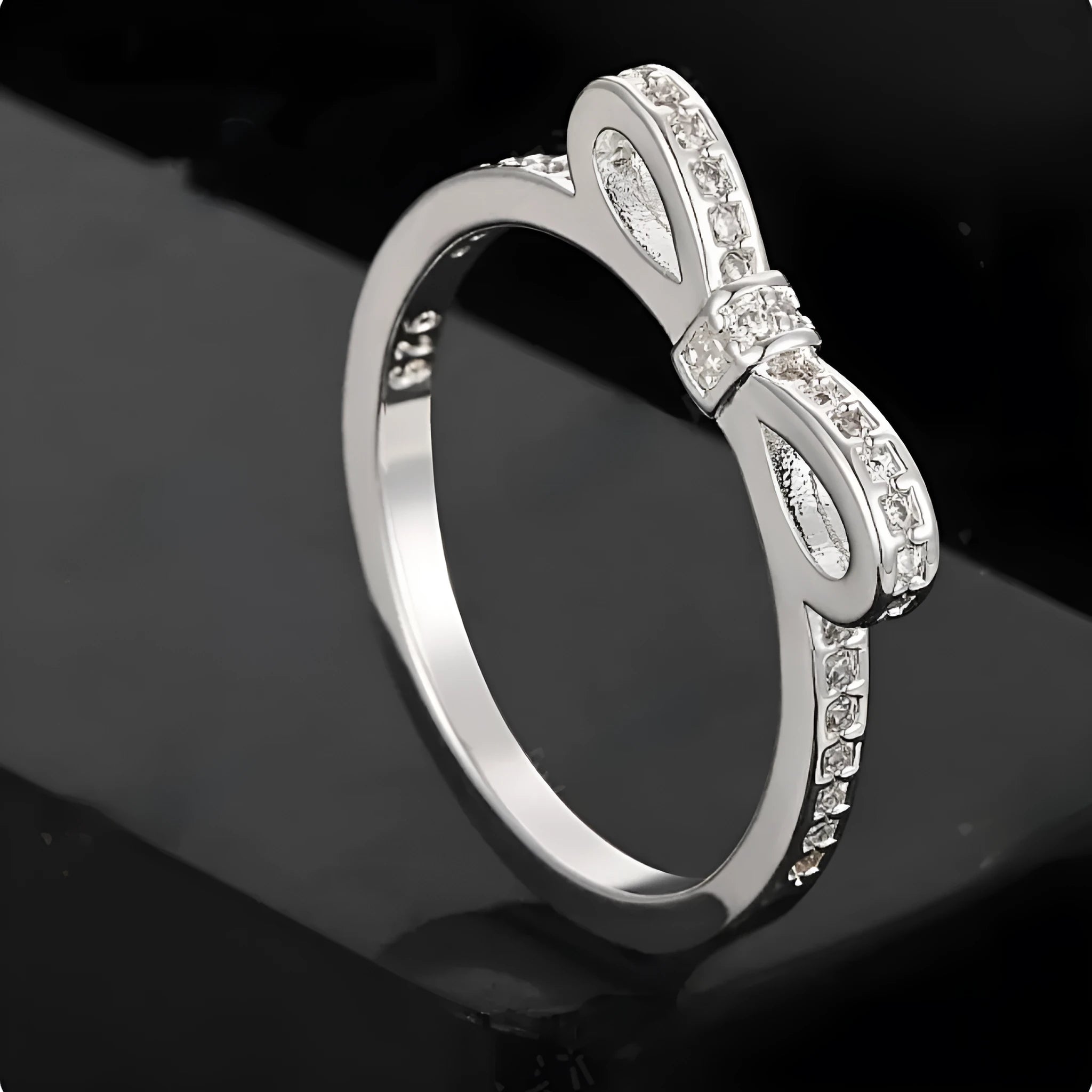 Silver bow-shaped rhinestone ring with zircon crystals on finger