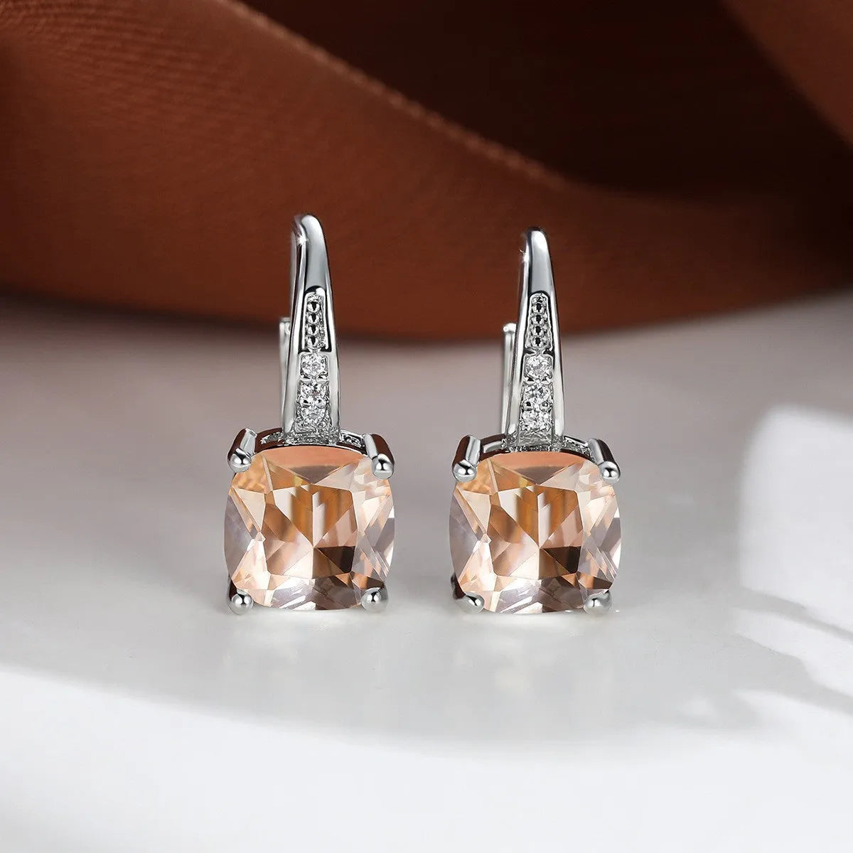 Square geometric ear hook earrings with zircon stones in an electroplated copper setting.