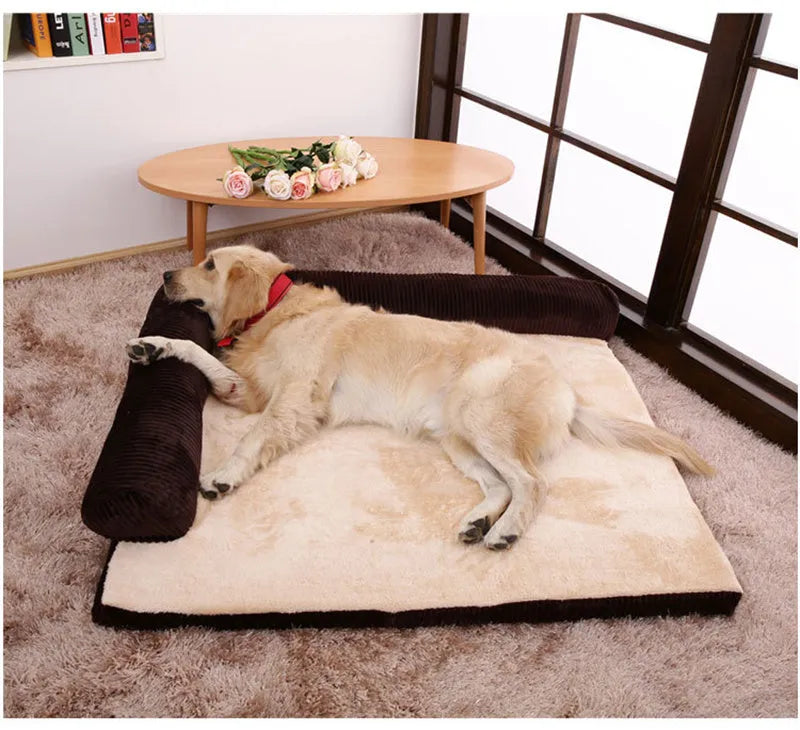 A corduroy pet sofa dog bed with a raised bolster, shown in a grey colour on a wooden floor.