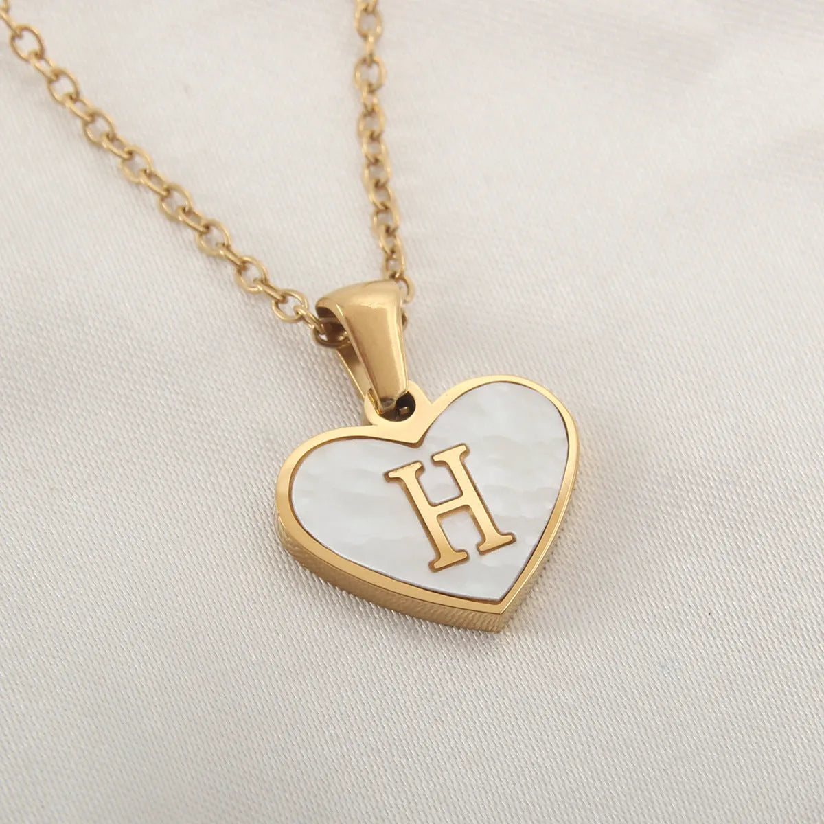 Gold plated heart-shaped personalised necklace with white shell charm on an adjustable chain.