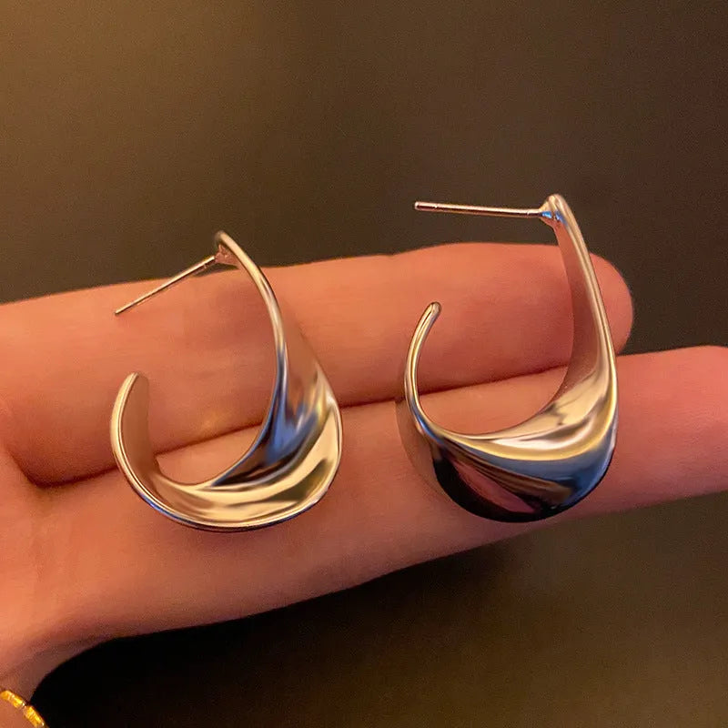 A pair of round, twisted geometric metal earrings with a gold electroplated finish.