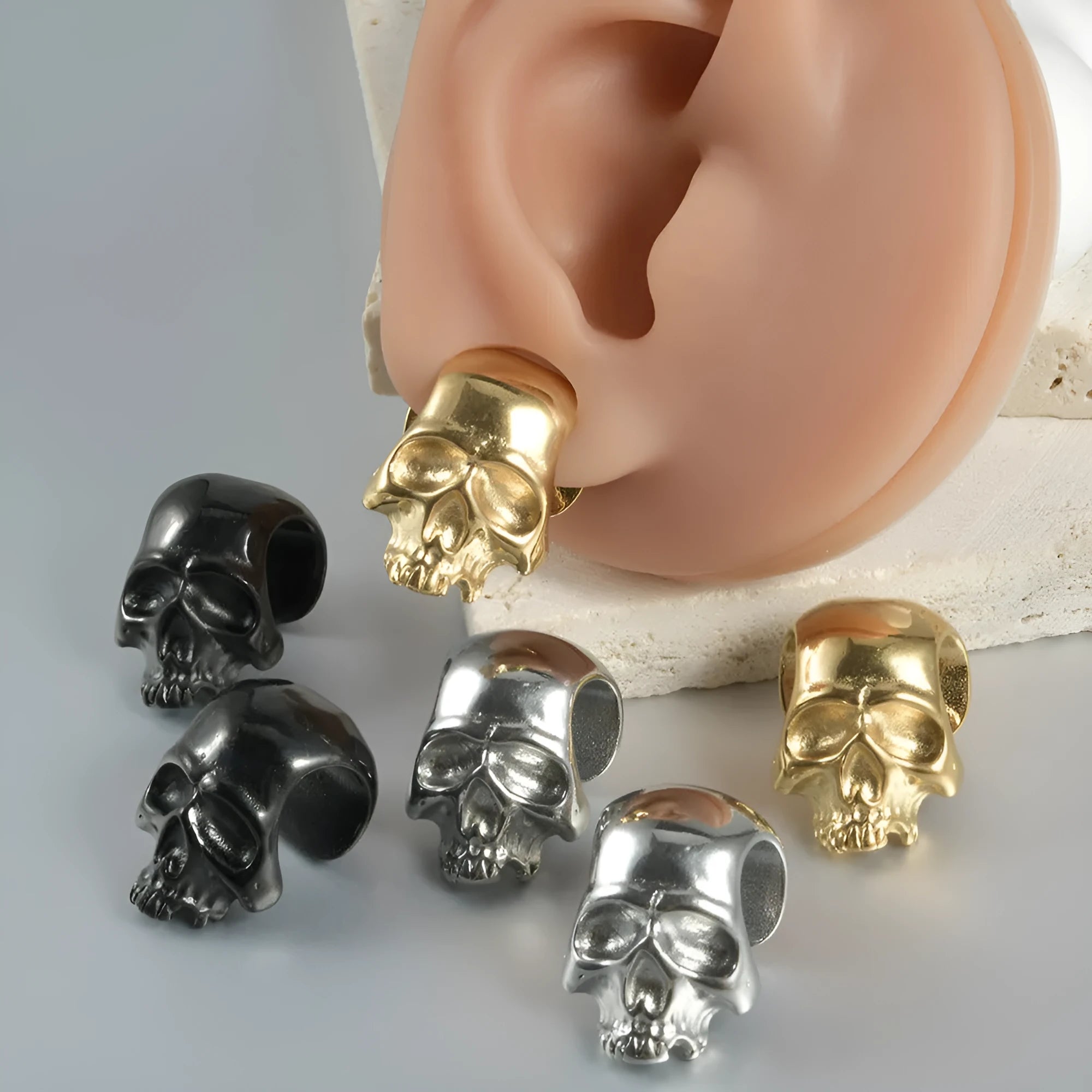 Stainless steel geometric earrings with hollow skull and Buddha head design in electroplated colour options.
