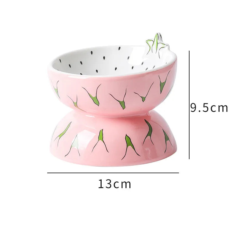 Ceramic elevated cat bowl with tilted surface in a colourful fruit pattern, showing its height and wide design.