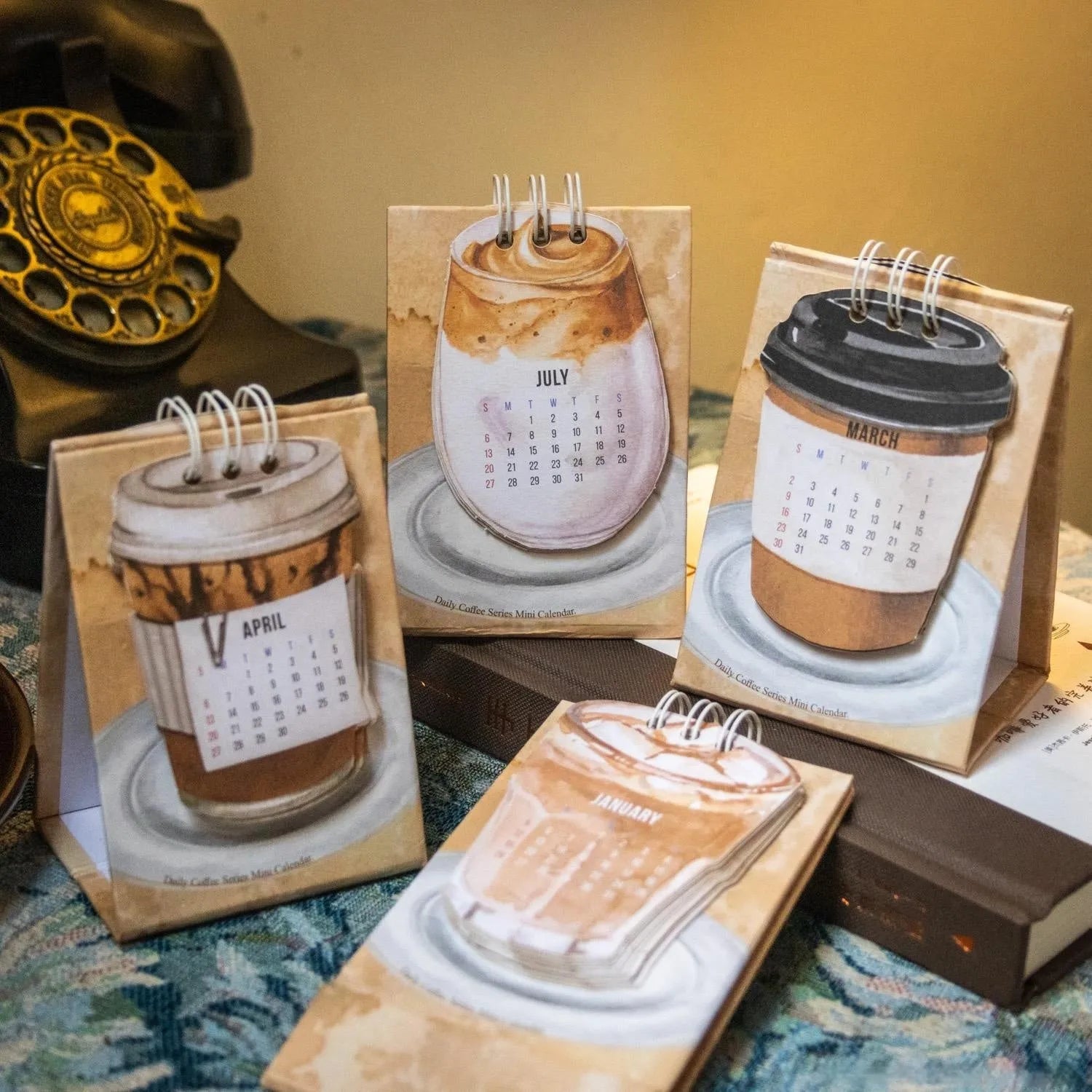 Mini A6 paper desk calendar for 2025 open to a monthly page with coffee-themed design.