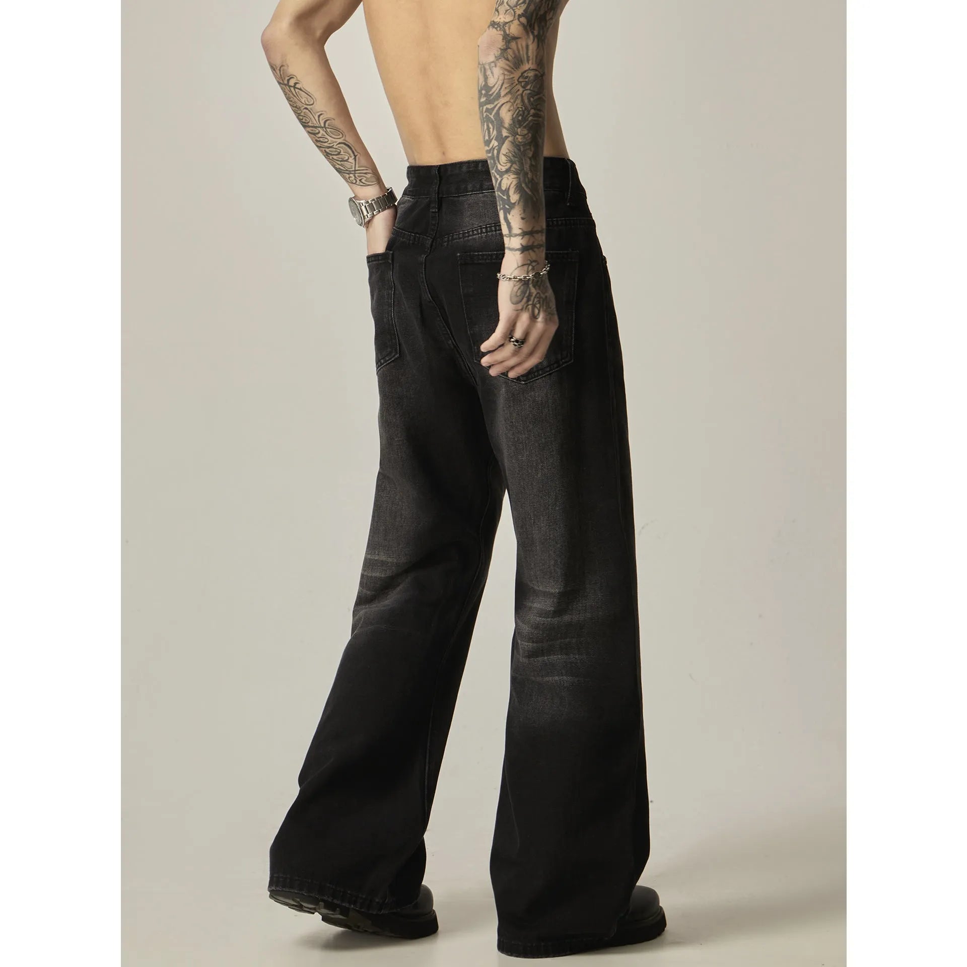 Man wearing black loose-fit straight-leg retro jeans in a casual setting.