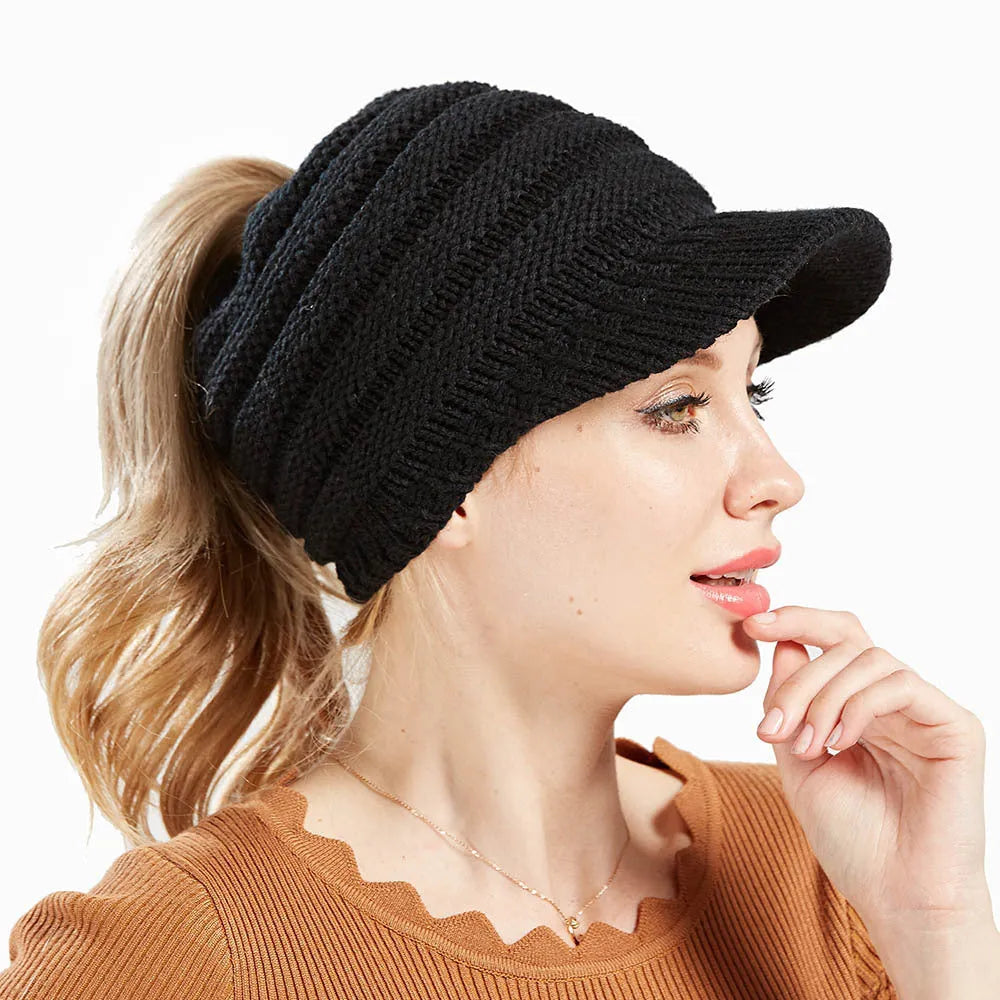 Woman wearing a soft knitted beanie with a ponytail pulled through the hole at the back.