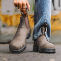 Vintage frosted brown leather Chelsea boot with round toe and low heel on a wooden surface.