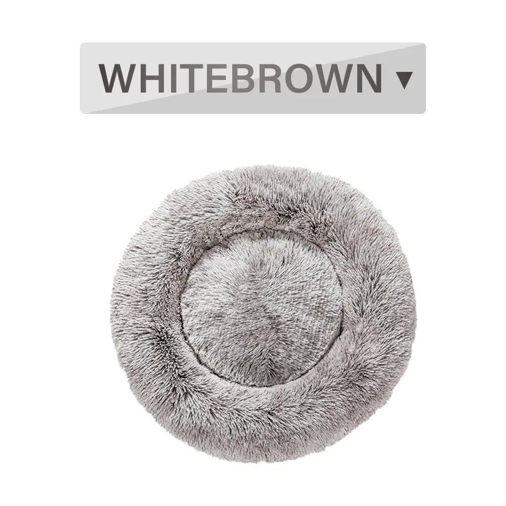 Fluffy donut-shaped dog bed in long plush material, shown in a light grey colour with a raised edge.
