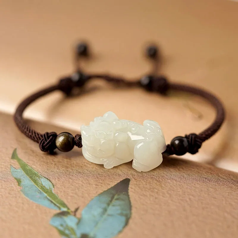A Hetian jade bracelet with braided black and red rope in a Chinese style design.