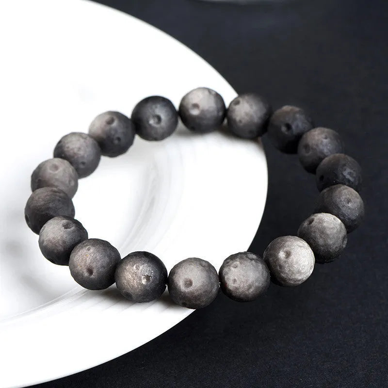 Natural obsidian crater ball bracelet with polished beads in silver or gold meteorite finish.