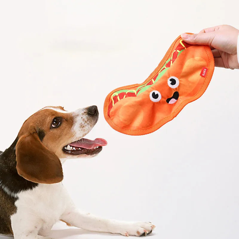 Colourful crinkle and squeaky dog chew toys shaped like a hamburger, fries, a hot dog, and a pizza on a plain background.