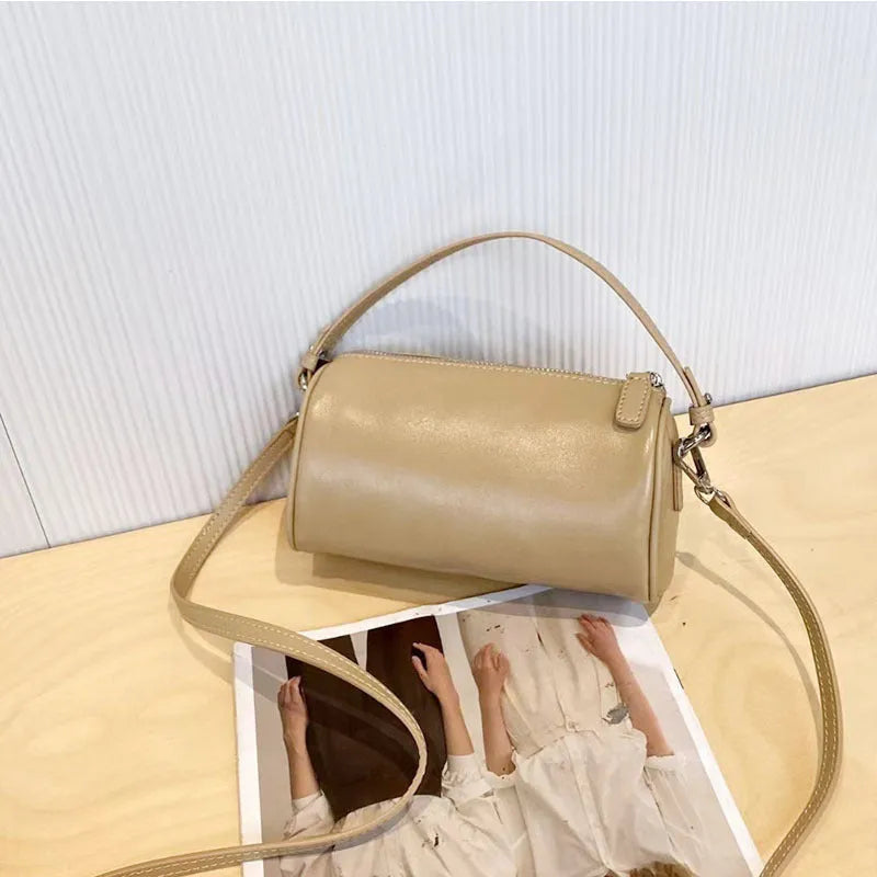 Vegetable-tanned leather crossbody phone bag with cylindrical shape and visible sewing thread detailing