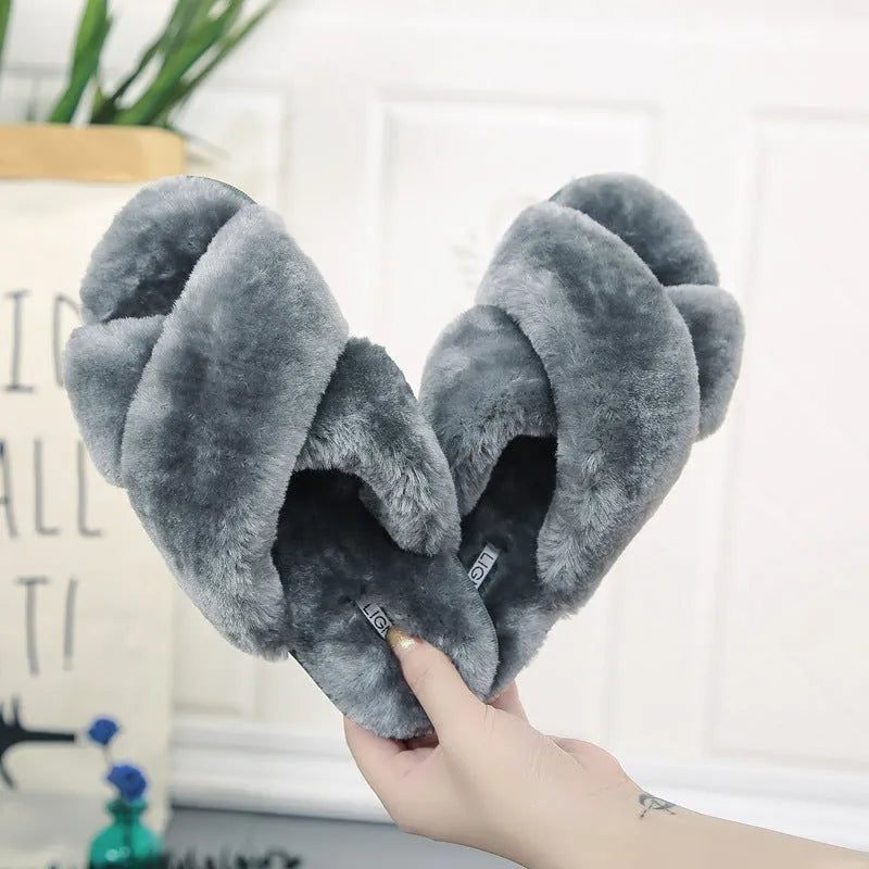 Women's black cross open-toe fur slippers with a patterned non-slip sole on a wooden floor