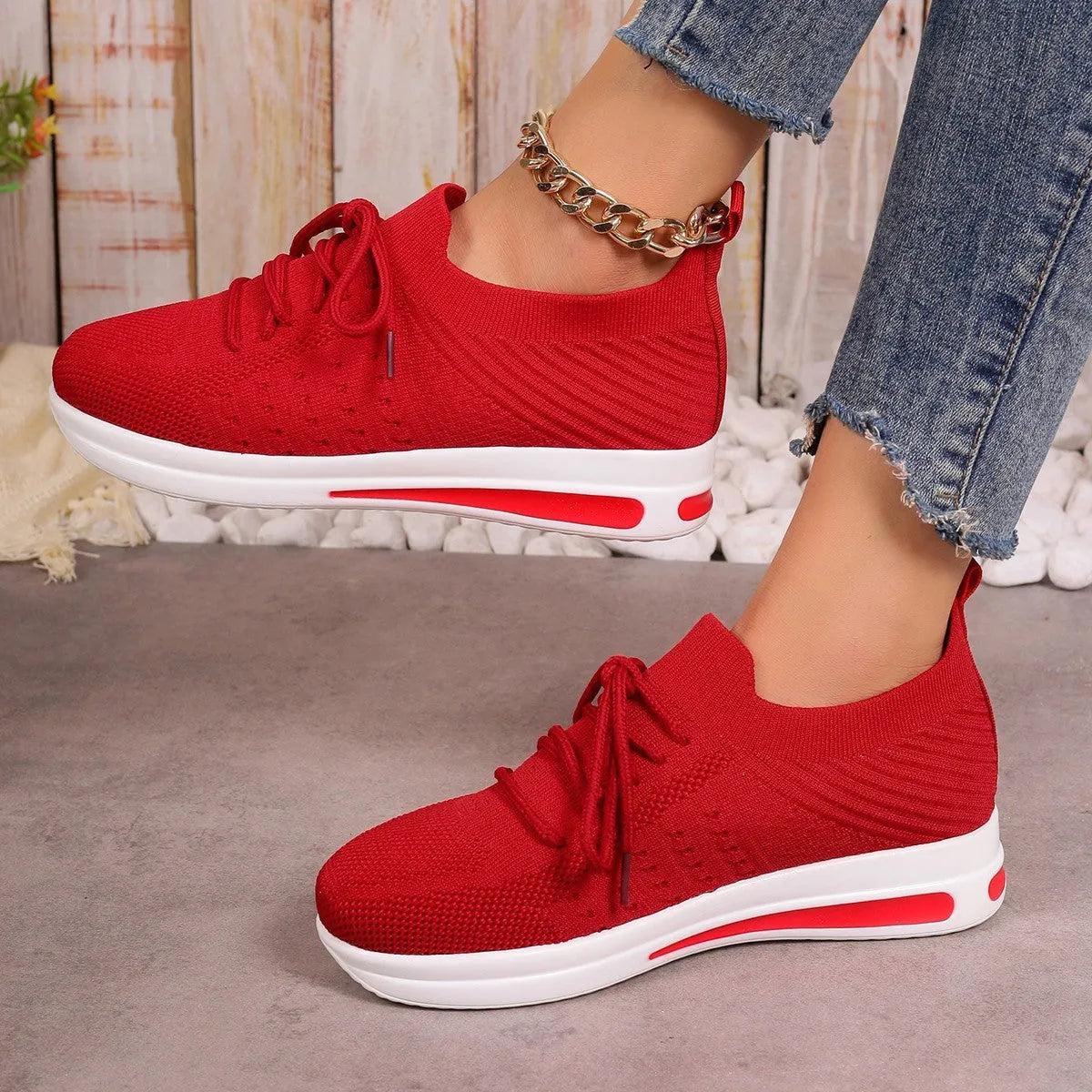 Women's low-top red fly-knit sneakers with round toe and white injection moulded sole on a light background.
