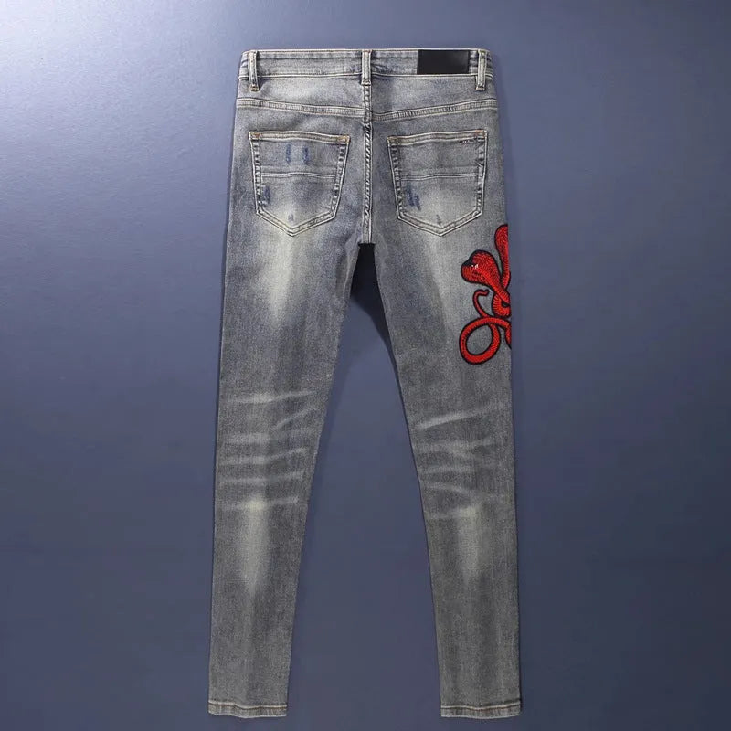 Slim fit jeans with a washed-out old colour finish, hole patches, and embroidery detail on the legs.