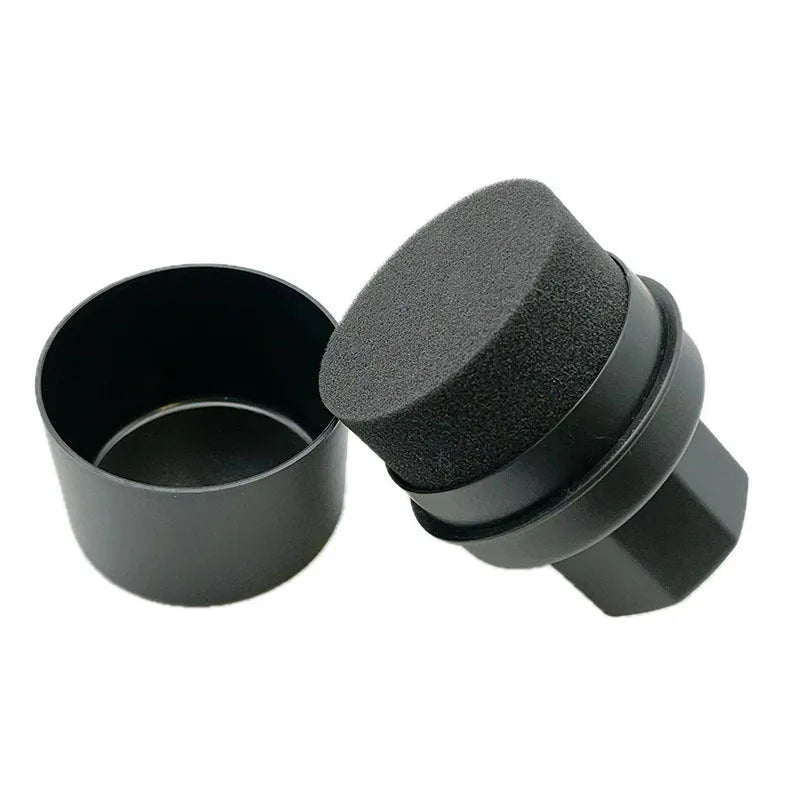 Hand-held black and red car tyre polishing sponge brushes with lids on a garage workbench.