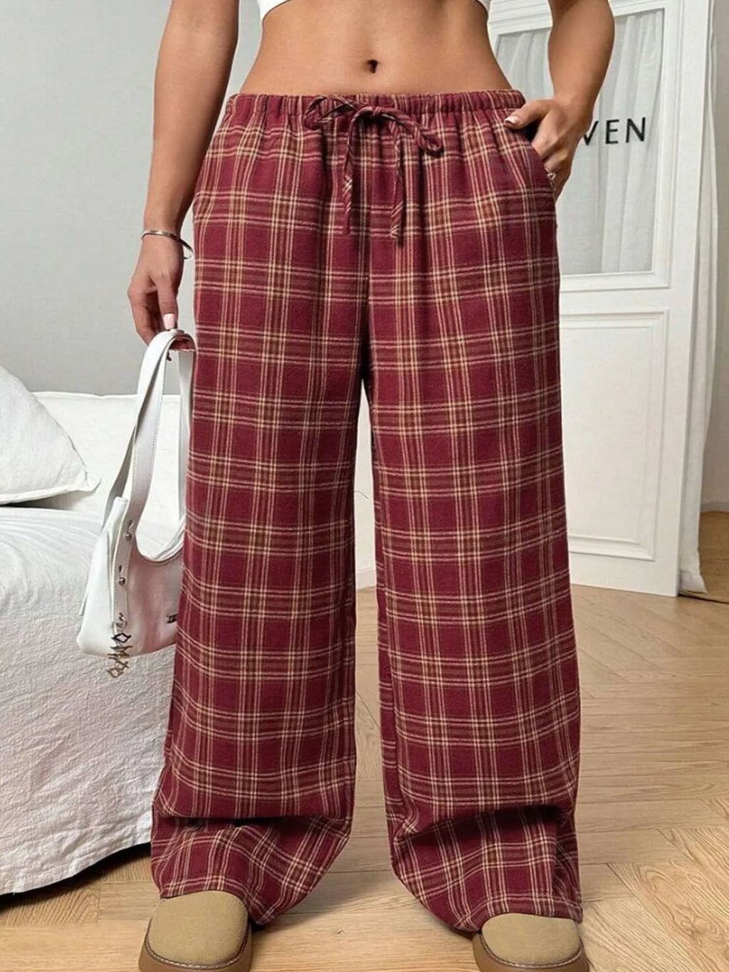 Red women's loose fit plaid trousers with drawstring waist and pockets on a mannequin.
