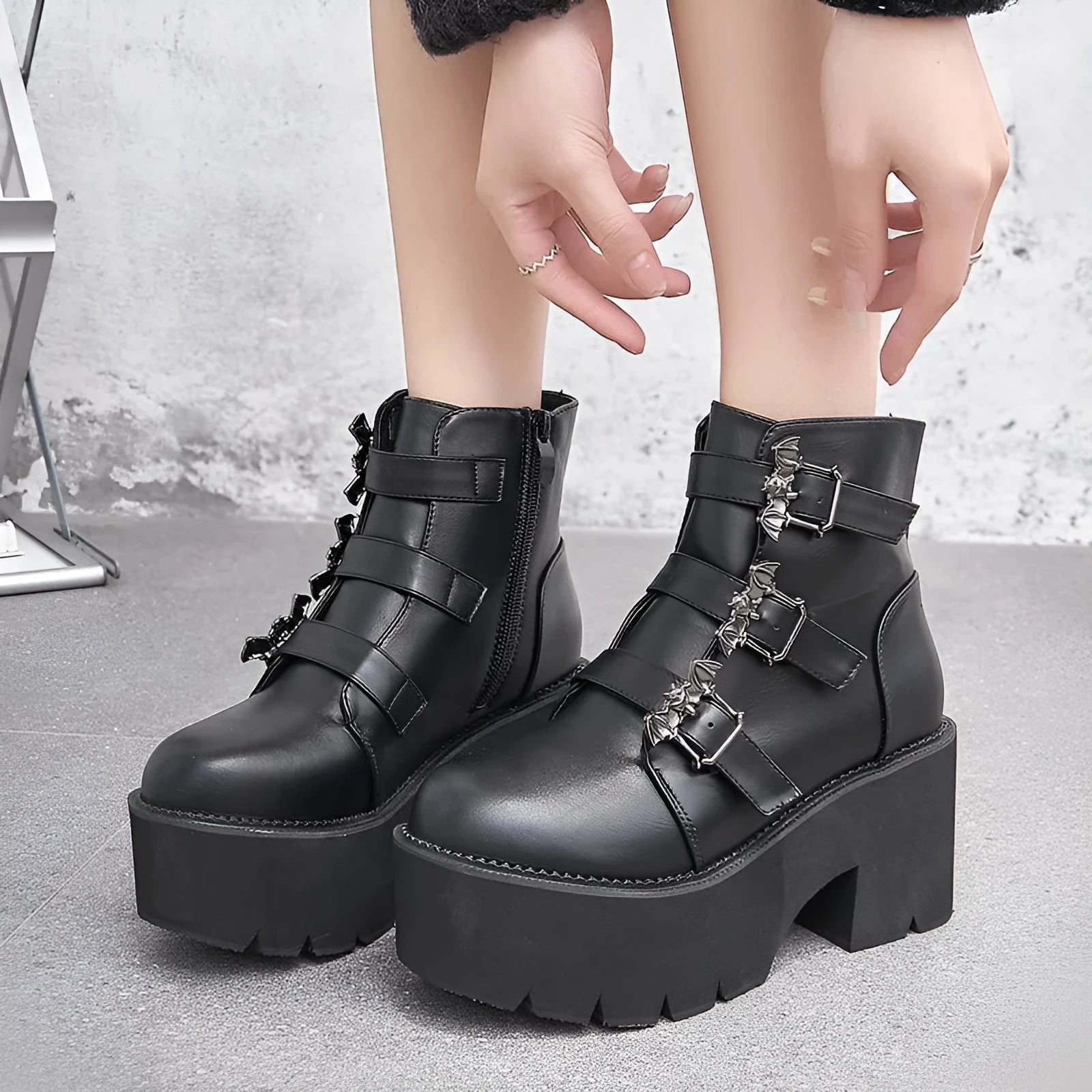 Black women's punk style ankle boots with bat buckle and side zip.