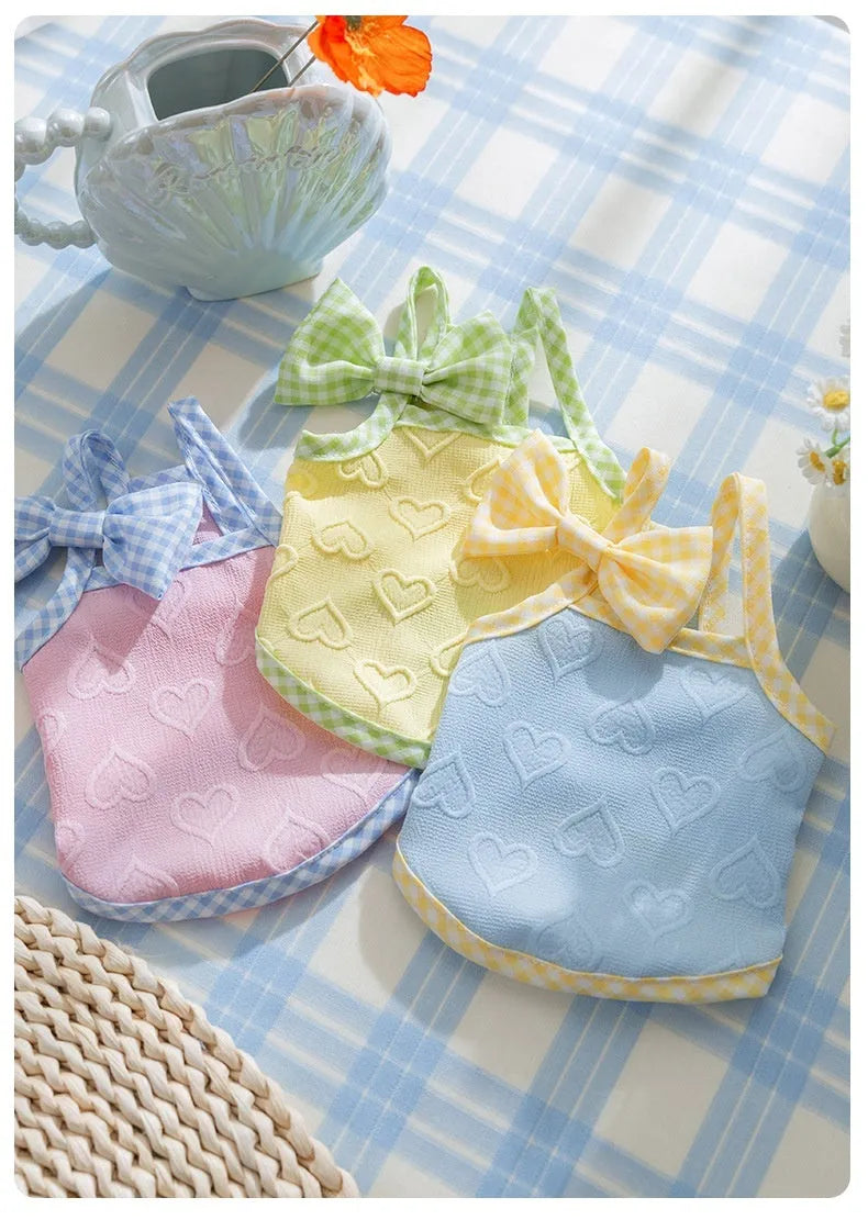 Small dog wearing heart pattern vest with bow suspenders in blue colour, showing elastic fit and decorative design