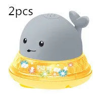 Whale-shaped electric bath toy spraying water with flashing lights, on a blue base.