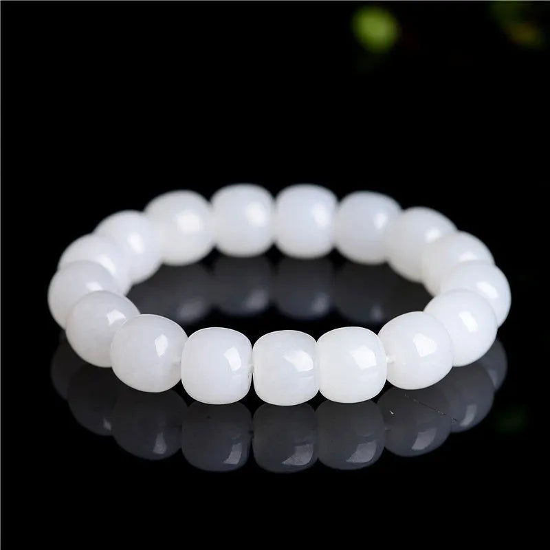 White Hetian jade barrel bead bracelet on a wrist, showing traditional unisex design.