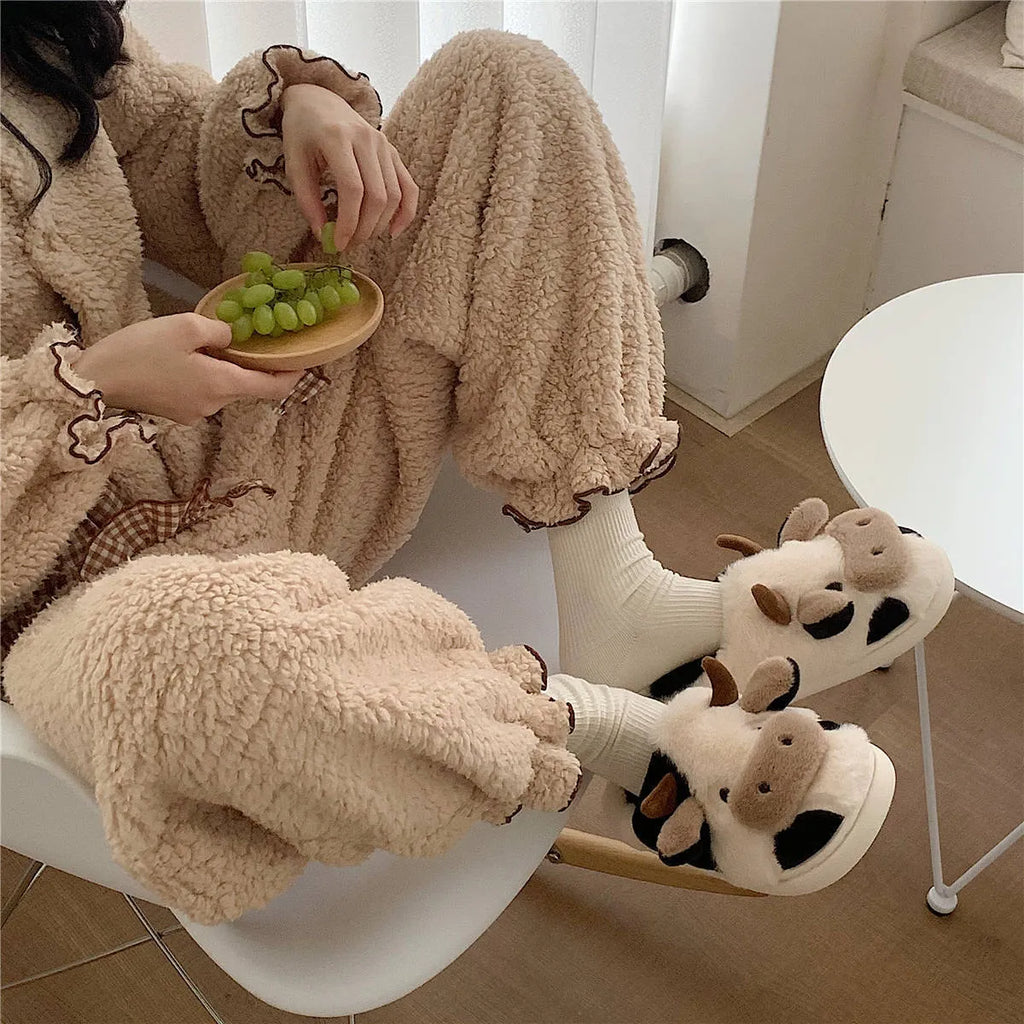 White plush cow slippers for women with a non-slip textured sole.