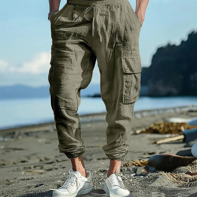Man wearing loose, ankle-tied linen trousers in a solid colour with visible pockets.