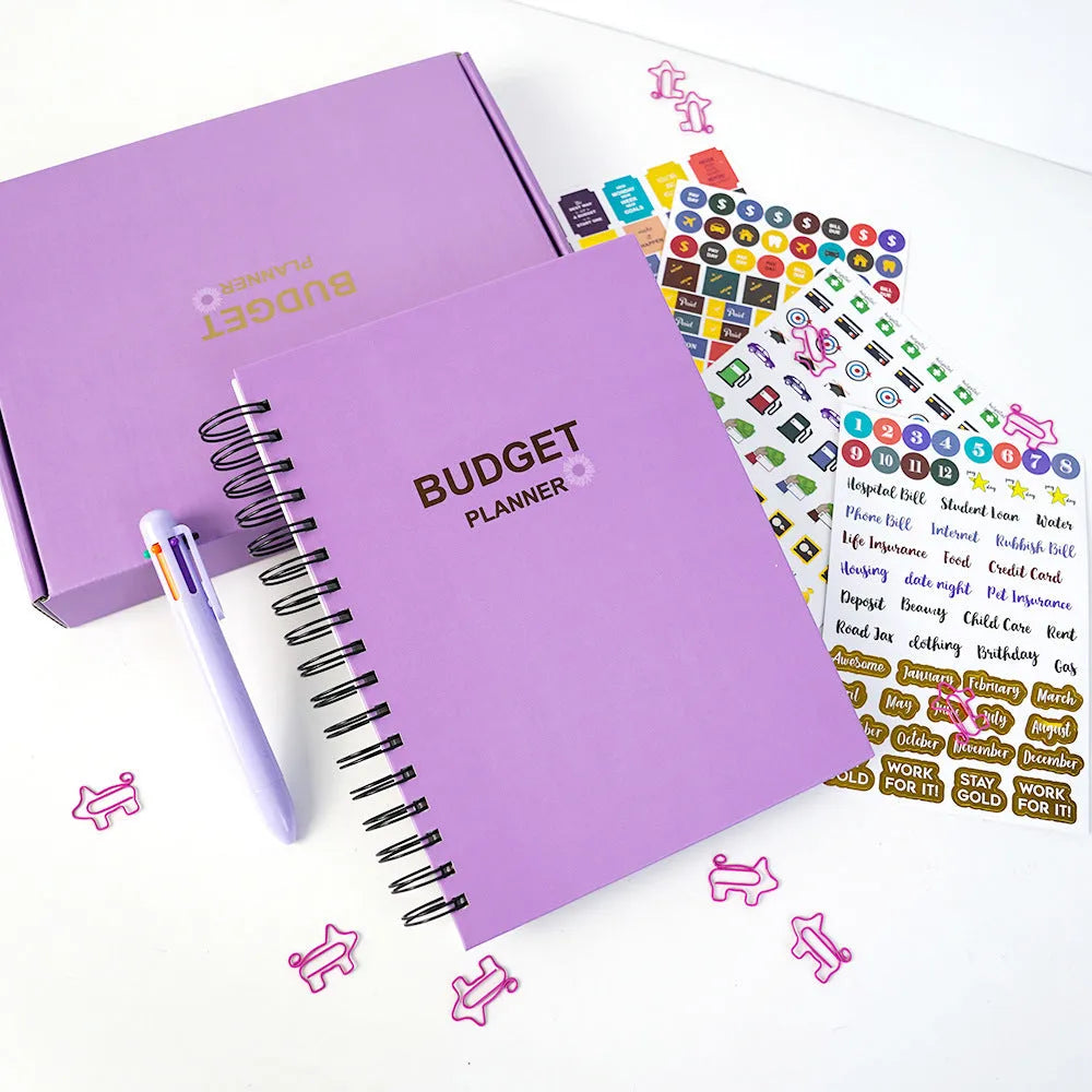 Purple A6 coil-bound budget notebook with pen and financial planning accessories