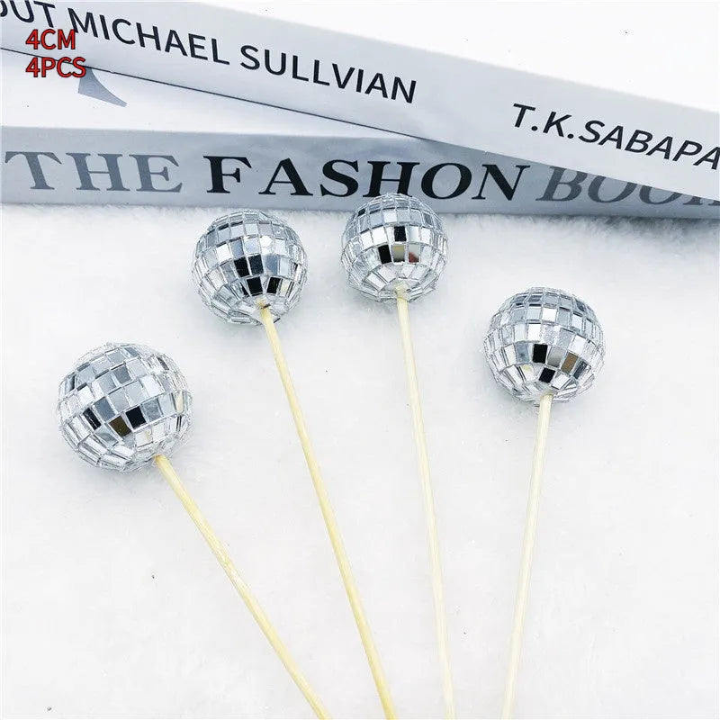 Silver reflective glass disco ball cake topper on a wooden stick for birthday party decoration.