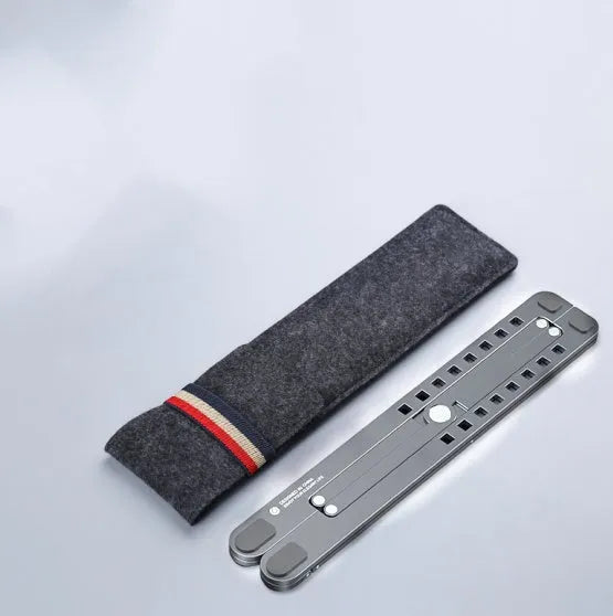 A folded aluminium laptop stand in silver next to an open laptop, demonstrating its compact size.