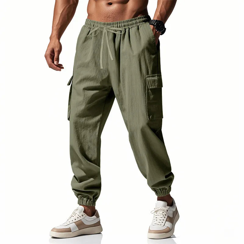 Man wearing loose, ankle-tied linen trousers in a solid colour with visible pockets.