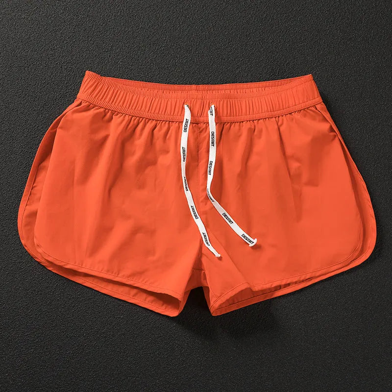 Men's loose orange beach shorts with elastic waistband on a sandy shore