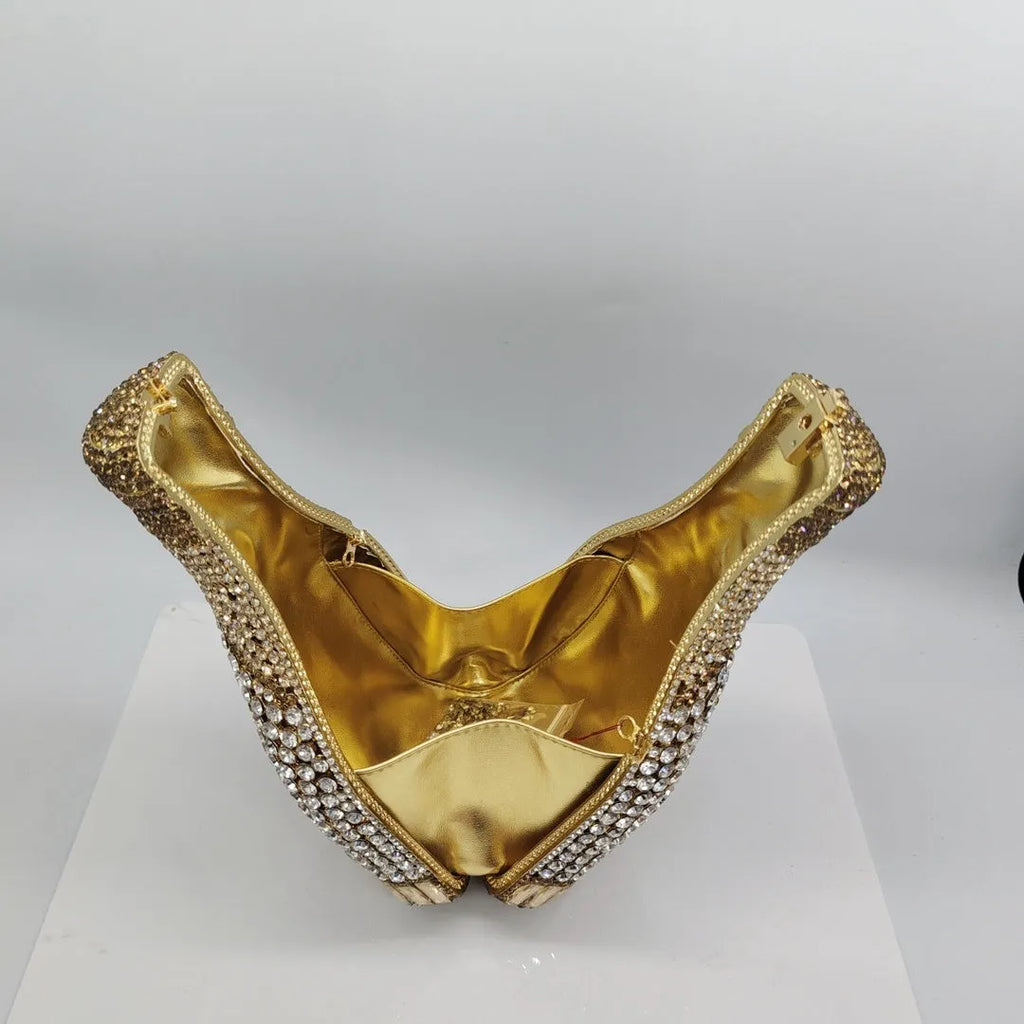 Gold hard-shell champagne bottle shaped evening clutch with rhinestones on a table.