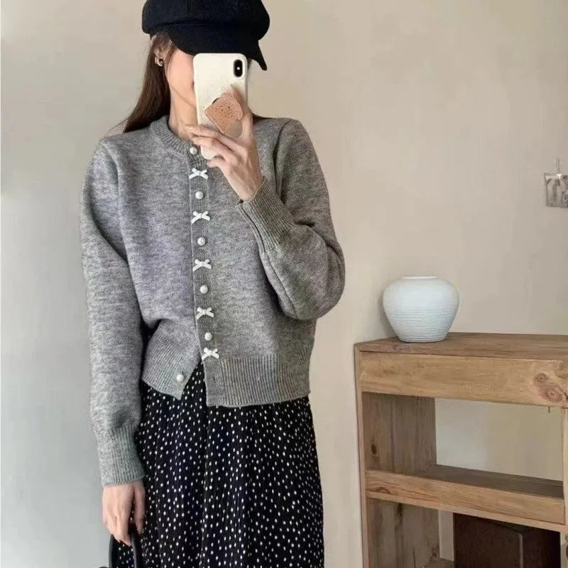 Women's solid colour cardigan sweater with pearl buttons in a light blue shade, shown open.