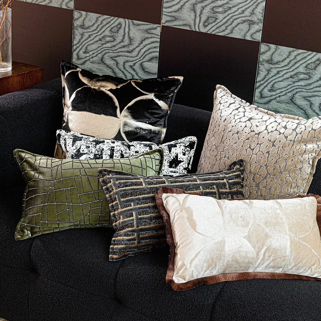 Black and gold abstract patterned flannel decorative pillow with removable cover on a grey sofa.