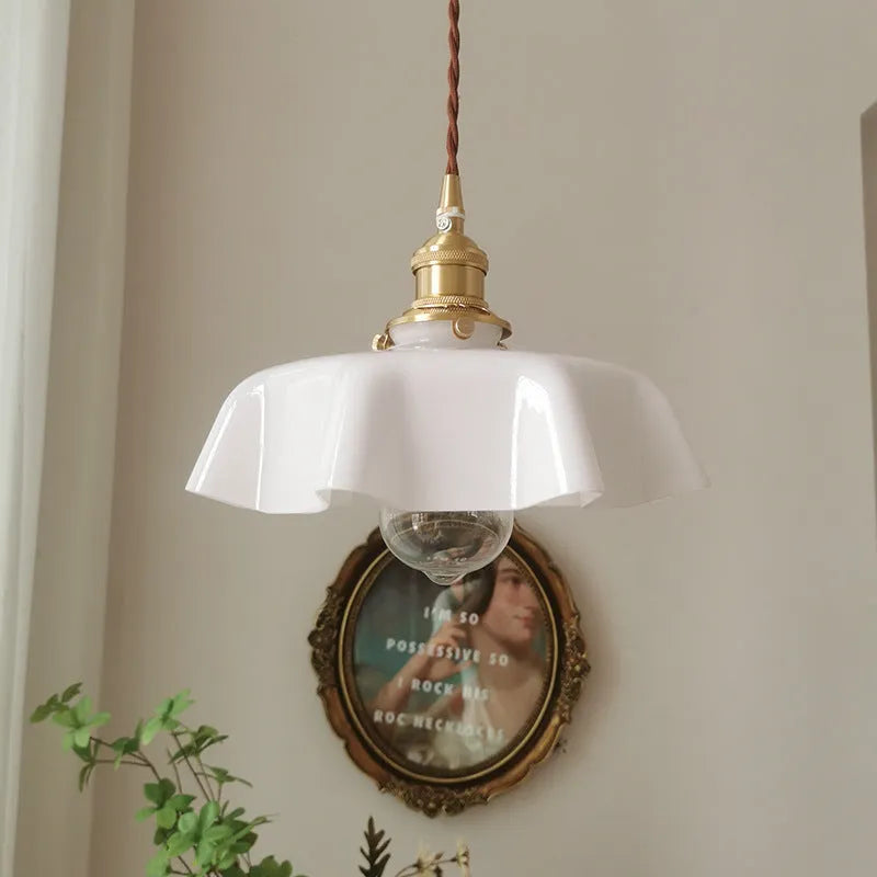 Medieval-style brass flower bud chandelier with a cream glass shade hanging from an adjustable cord.