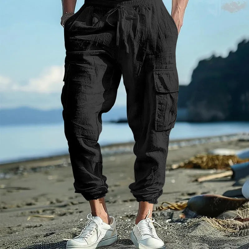 Man wearing loose, ankle-tied linen trousers in a solid colour with visible pockets.