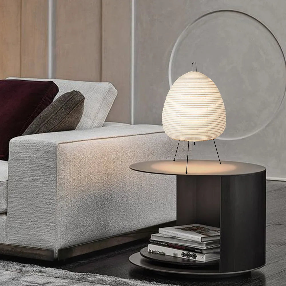Japanese style handmade rice paper lantern table lamp with aluminium base on a wooden table.