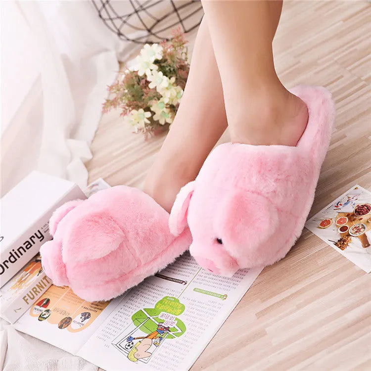Pink pig-shaped plush slippers for adults on a white background.