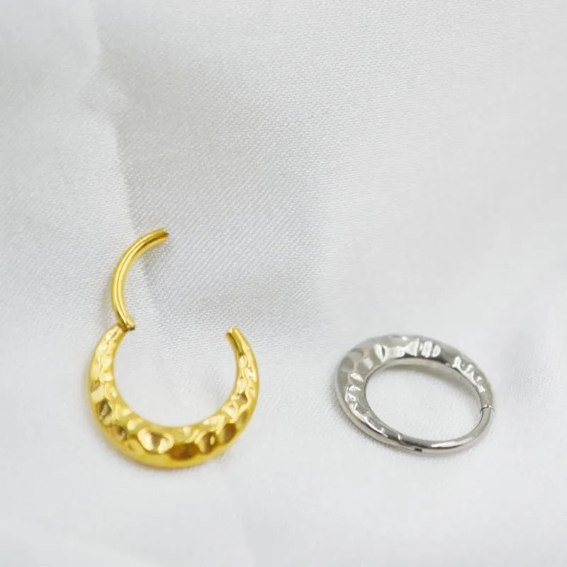 Close-up of a titanium alloy concave-convex nose ring in gold finish, showing carved detail and ring shape.