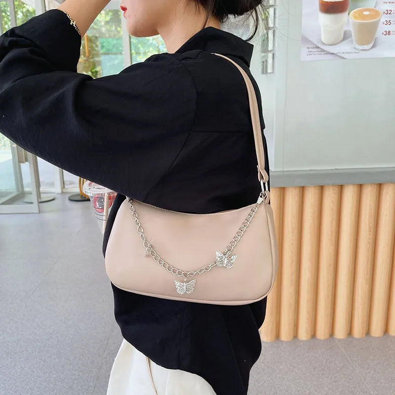 Retro-style square crossbody handbag with a butterfly clasp on its chain strap.