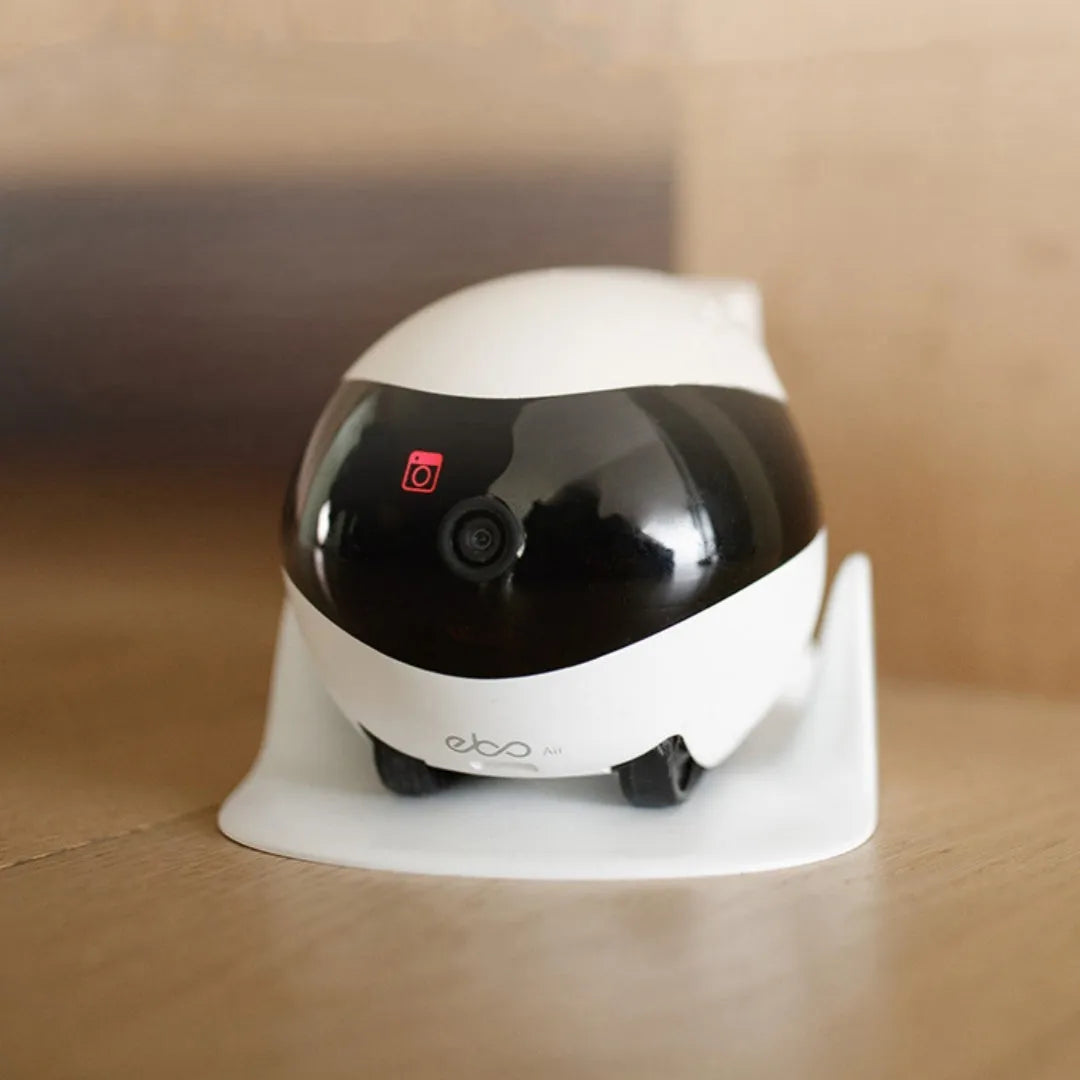 White smart home mobile surveillance robot camera on a charging dock.