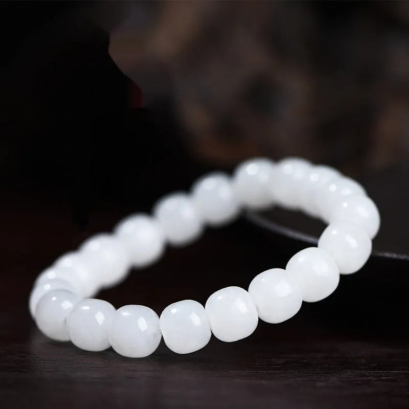 White Hetian jade barrel bead bracelet on a wrist, showing traditional unisex design.