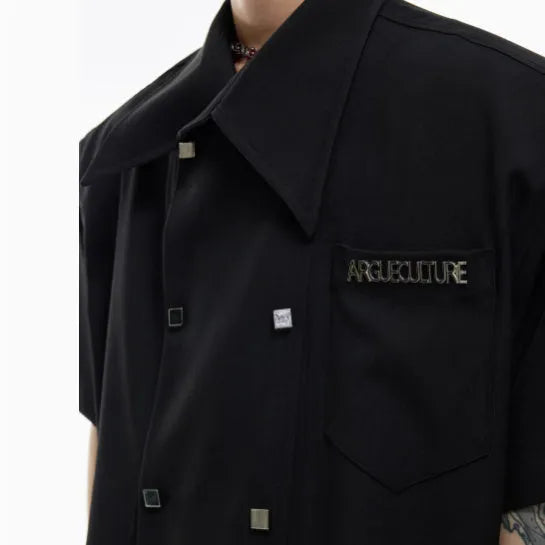 Man wearing a loose-fit black short-sleeved casual shirt with metal button decoration on the front.