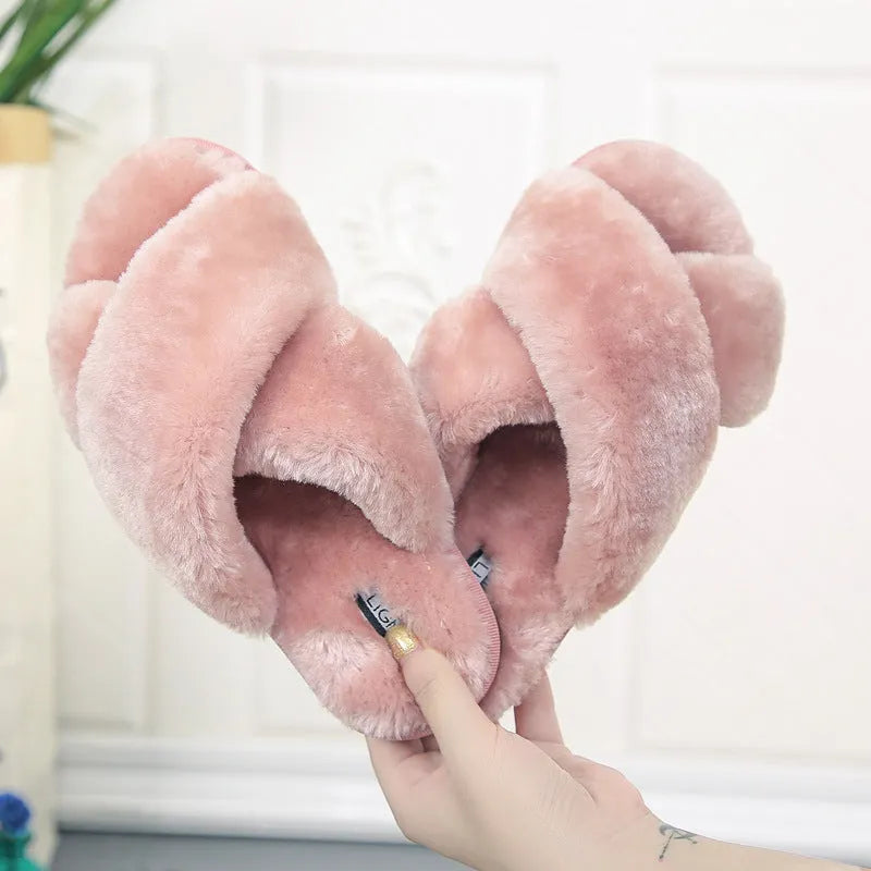 Women's black cross open-toe fur slippers with a patterned non-slip sole on a wooden floor