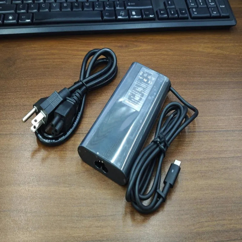 Black 65W Type-C laptop power adapter with multiple international power cords for UK US EU AU and ZA plugs.