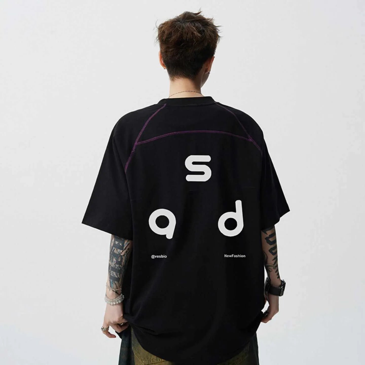 Man wearing a black loose-fit cotton T-shirt with a letter print on the chest.