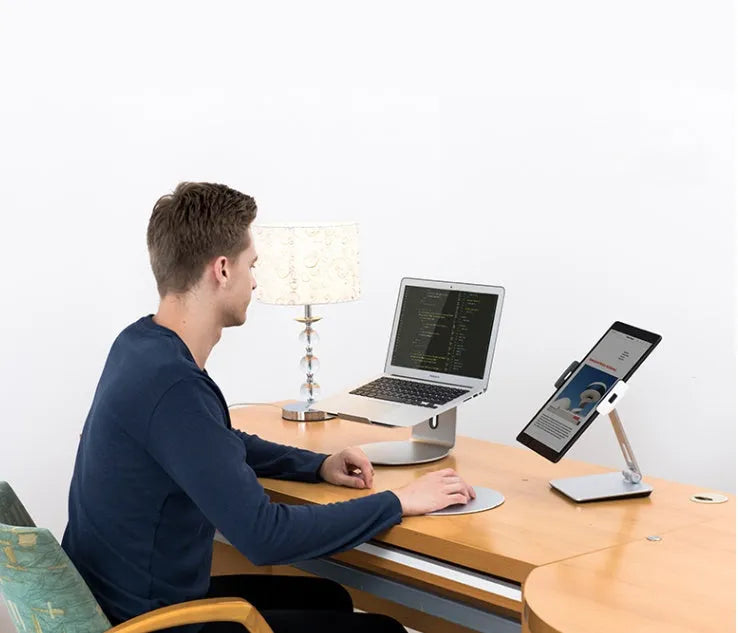 Folding aluminium phone and tablet stand on a desk, shown in silver colour with 360-degree rotation.