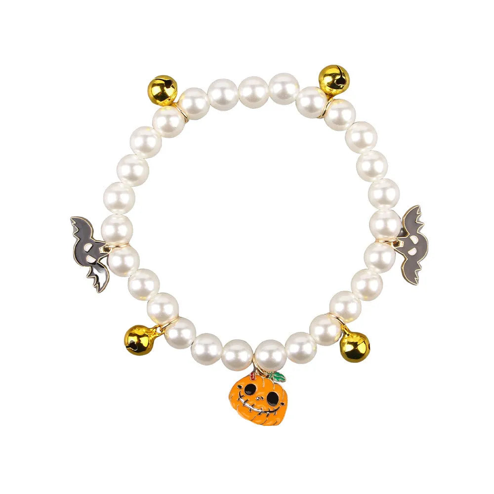 Adjustable simulated pearl necklace cat collar with a Halloween pumpkin charm in purple ghost, skull, or smile designs.