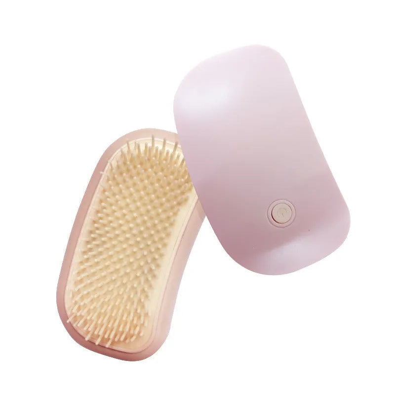 Pink handheld electric pet grooming massage brush with TPE teeth on a white background.